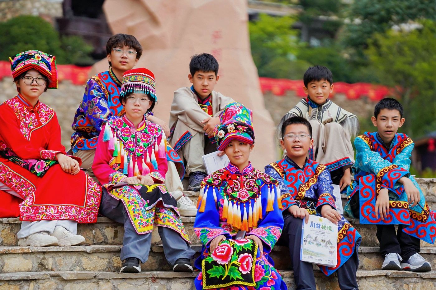 孩子们穿着民族服饰在村寨前合影