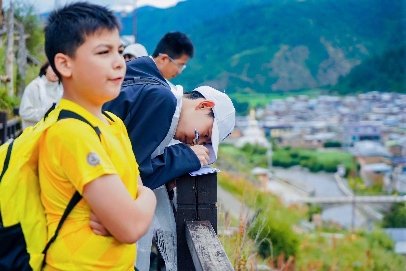 男孩在观景台俯瞰山谷里的藏族村寨