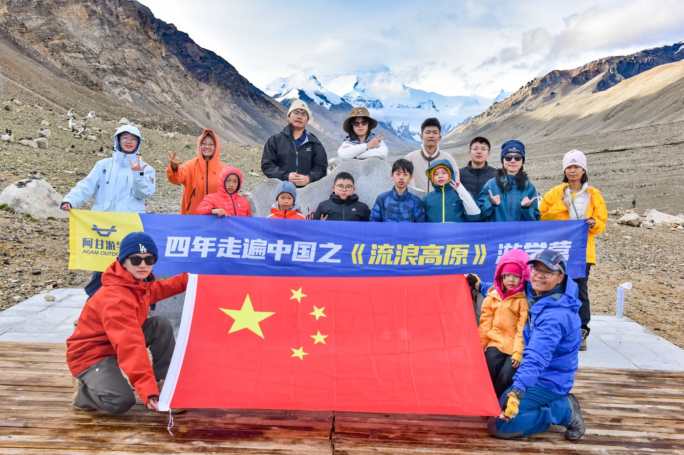 孩子们在高原上展开国旗与营旗合影